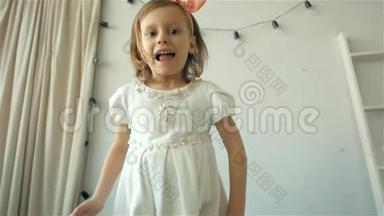 一个快乐可爱的小女孩，穿着白色连衣裙，在床上<strong>蹦蹦</strong>跳跳，微笑着的小孩子